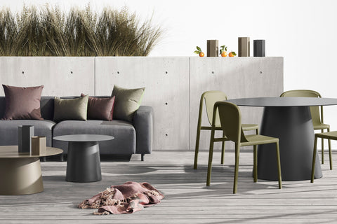 Blu Dot Circula dining, coffee and side tables on an outdoor deck beside a grey sofa