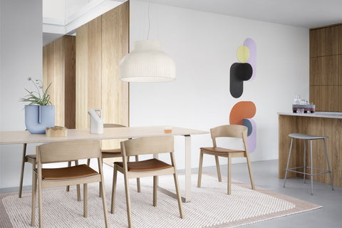 Muuto Cover Side Chairs in Oak with Cognac Refine Leather seats around a light wood dining table under a Strand pendant
