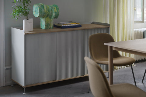 Muuto Enfold Sideboard in lacquered oak with grey ridged sliding doors along a dining room wall