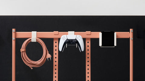 Pedestal Hook Mount, Controller Mount and Apple TV Mount in Pearl on a TV stand frame, holding a coiled cable, a game controller and a media box