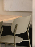 Audo Copenhagen Co Dining Chair, Outdoor, close-up shot of the back of the olive-colored Co Dining Chair, Outdoor, positioned next to a light wood dining table