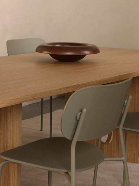 Audo Copenhagen Co Dining Chair, Outdoor, an olive Co Dining Chair, Outdoor placed by a light oak Androgyne Dining Table with a dark wood Rond Bowl