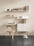 ome office setup with String® System white floor panels, desk, shelves, and cabinet against a beige wall.
