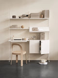 String Furniture white modular shelving with desk, cabinet, and oak chair in a minimalist home office