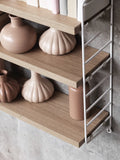 Oak String® Pocket shelf with white side panels styled with blush ceramic vases and books – Scandinavian design shelving