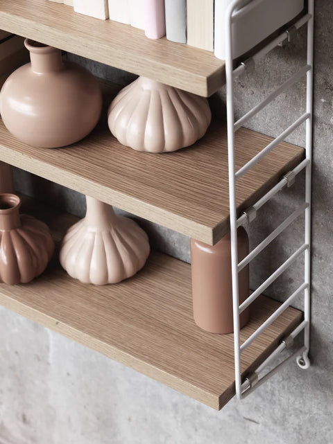 Oak String® Pocket shelf with white side panels styled with blush ceramic vases and books – Scandinavian design shelving