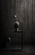 Museum Side Table in black styled with ceramic vase, Scandinavian accent piece against dark wood wall