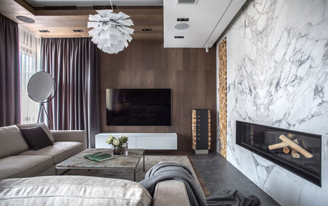 Modern living room with a PH Artichoke pendant marble fireplace wood panel TV wall and stacked firewood detail