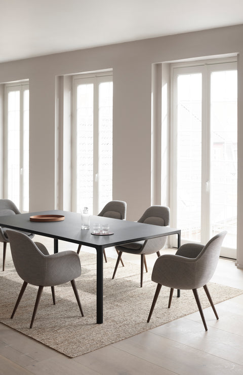 Swoon Dining Chairs with dark wood legs and grey upholstery arranged around a black rectangular dining table.
