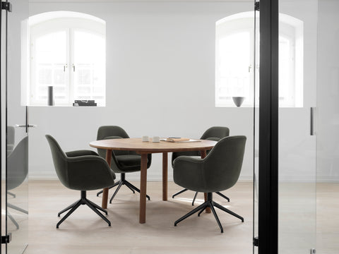 Fredericia Swoon swivel chairs in dark green upholstery around round wooden dining table in modern minimalist meeting room