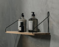 Frama Single Shelf, Natural Oak in Black, oak shelf with black brackets on a concrete wall holding two pump bottles