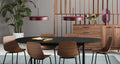 Two Blu Dot Bobber Large Pendants in oxblood above a black oval dining table with walnut shell chairs and a walnut sideboard