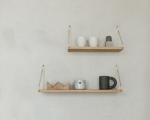 Frama Single Shelf, Natural Oak in Brass, two oak shelves on brass brackets with cups, a tin and a dark mug on a grey wall