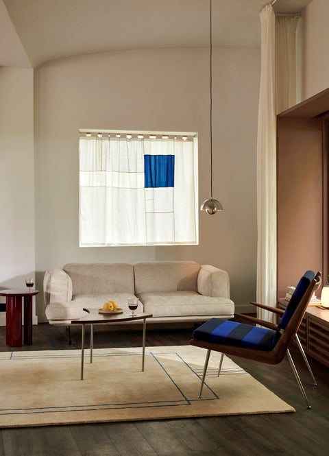 Modern interior with &Tradition Pinwheel HM7 End Table in walnut and stainless steel beside beige sofa and armchair