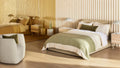 Blu Dot Beau Table Lamp in putty styled on a nightstand in a warm modern bedroom setting