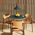 Blu Dot Apt Round Cafe Table with navy green linoleum top and white oak base styled in a warm dining nook