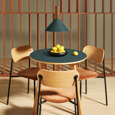 Blu Dot Apt Round Cafe Table with navy green linoleum top and white oak base styled in a warm dining nook