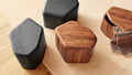 Acacia and black-stained acacia Hoard Tall Side Tables with Storage next to a green velvet lounge chair by a fireplace