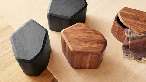 Acacia and black-stained acacia Hoard Tall Side Tables with Storage next to a green velvet lounge chair by a fireplace