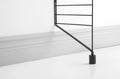 Black floor panel extension attached to String® System panel, detail view at baseboard