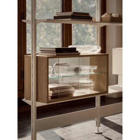 String Furniture Pira shelving system with black poles and walnut cabinets, modular steel shelving styled with books