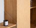 Frama Shelf Library Medium Cabinet Section in Natural Oak, close up of the thin steel bracket under an oak shelf beside the cabinet side panel