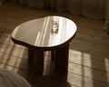 Frama Farmhouse Side Table in Natural Oak, rounded pond shaped top with a glass of water, sunlight striping a plank floor