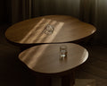 Frama Farmhouse Coffee Table in Natural Oak, two rounded oak tops overlapping, a glass jug above and a glass of water below in sunlight