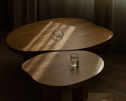 Frama Farmhouse Coffee Table in Natural Oak, two rounded oak tops overlapping, a glass jug above and a glass of water below in sunlight