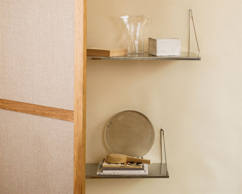 Frama Single Shelf, Stainless Steel, two shelves past a linen and wood screen, glass vase above and a round tray below