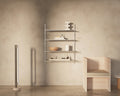 Frama Shelf Library Single Section in Stainless Steel, steel shelves with a bowl, books and objects beside a pale timber bench