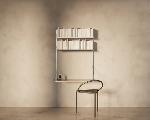 Frama Shelf Library Desk Section in Stainless Steel, steel shelf of books above a desk shelf with a dark curved back chair pulled up to it