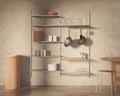 Frama Shelf Library Double Section in Stainless Steel, tall steel shelving with stacked plates and glassware, pans and ladles hanging from a rail