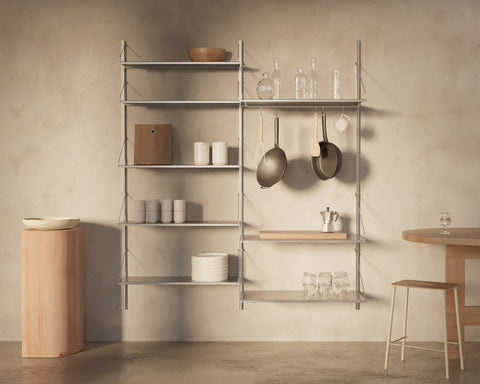 Frama Shelf Library Double Section in Stainless Steel, tall steel shelving with stacked plates and glassware, pans and ladles hanging from a rail