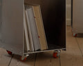 Frama Rivet Cart in Aluminum, cart packed with upright books and portfolios, rolling on castors over a wooden floor