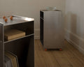 Frama Rivet Cart in Aluminum, two metal carts side by side against a plaster wall, one topped with a wooden board and handles