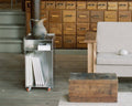 Frama Rivet Cart in Aluminum, metal cart holding upright magazines beside an apothecary chest, a jug resting on the rim