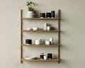 Frama Shelf Library Add-on Section in Natural Oak, one bay of oak shelves on a sage wall with stacked plates, black and white pots and a plant