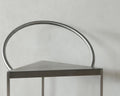 Frama Triangolo Chair in Stainless Steel, close up of the tubular hoop back rising from the triangular seat against a concrete wall