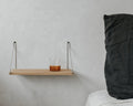 Frama Single Shelf, Natural Oak in Stainless Steel, oak shelf on steel brackets holding a tumbler of amber drink beside a dark cushion