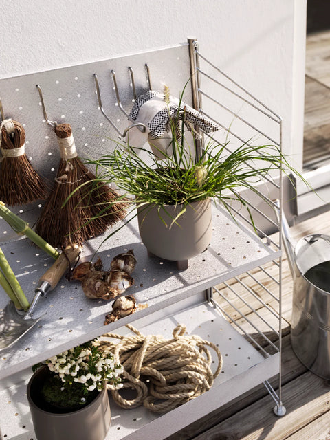 Close-up of galvanized 33.5"H String™ System floor panels with pegboard shelves and gardening accessories