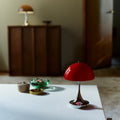 Louis Poulsen Panthella 160 portable table lamp in red on a white tabletop in a warm interior