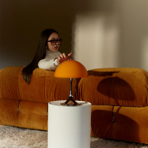 Louis Poulsen Panthella 250 portable lamp in orange as a person adjusts the touch control in a living space