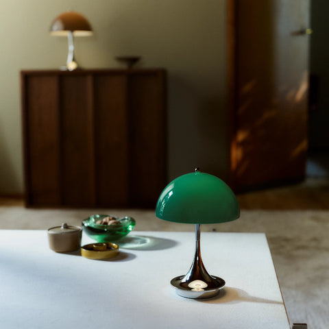 Louis Poulsen Panthella 160 portable table lamp in green placed on a white tabletop in a softly lit interior