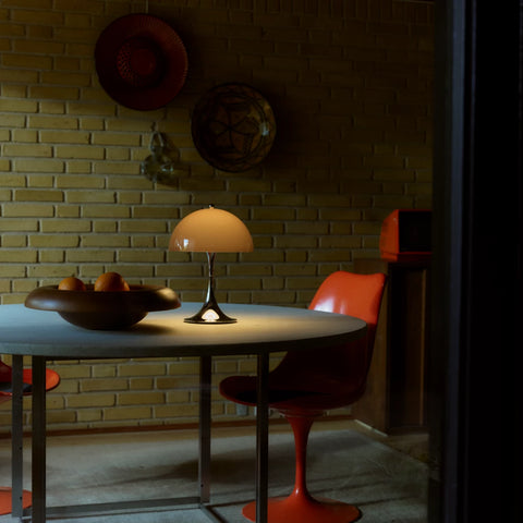 Louis Poulsen Panthella 250 portable lamp in brown illuminating a dining table with brick wall backdrop
