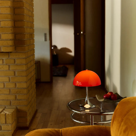 Louis Poulsen Panthella 250 portable lamp in red on a round glass side table in a warm interior hallway