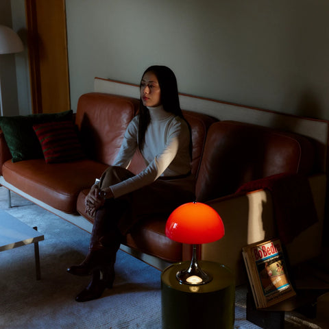 Louis Poulsen Panthella 250 portable lamp in red on a side table next to a leather sofa in a living room