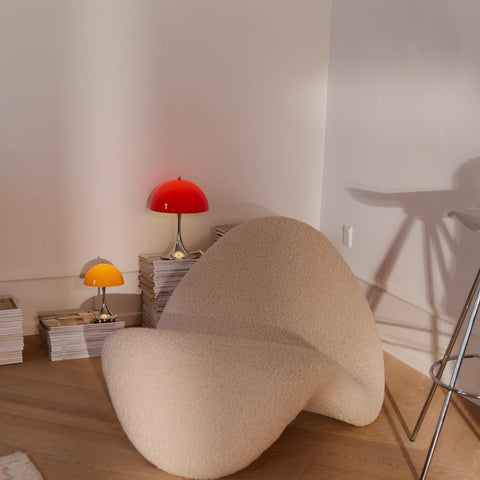 Louis Poulsen Panthella 160 portable lamp in red illuminating a cozy reading corner with sculptural lounge chair