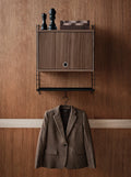 Walnut String® System cabinet with flip door wall-mounted, styled with decorative objects and jacket storage