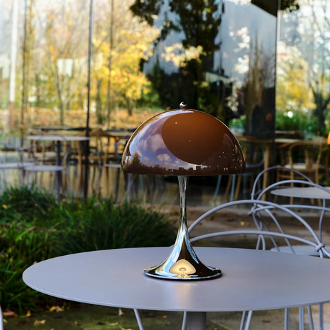Louis Poulsen Panthella 250 portable lamp in brown on an outdoor café table surrounded by greenery